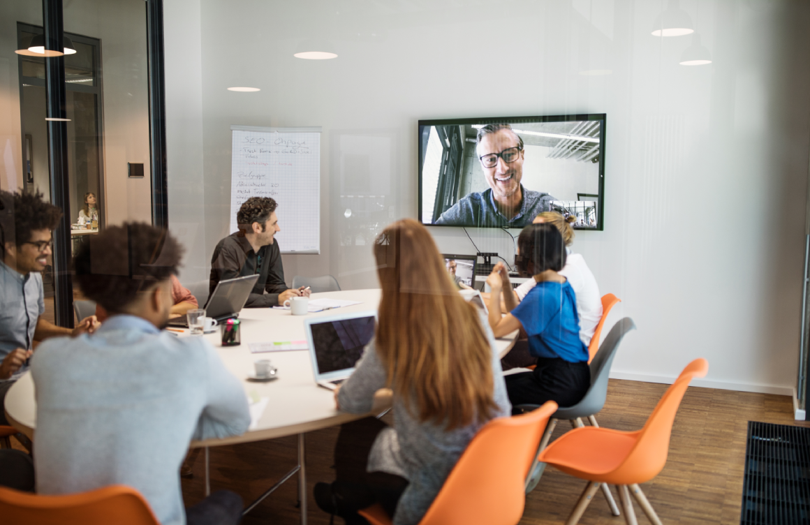 group of people sitting in conference room looking at the video conference screen